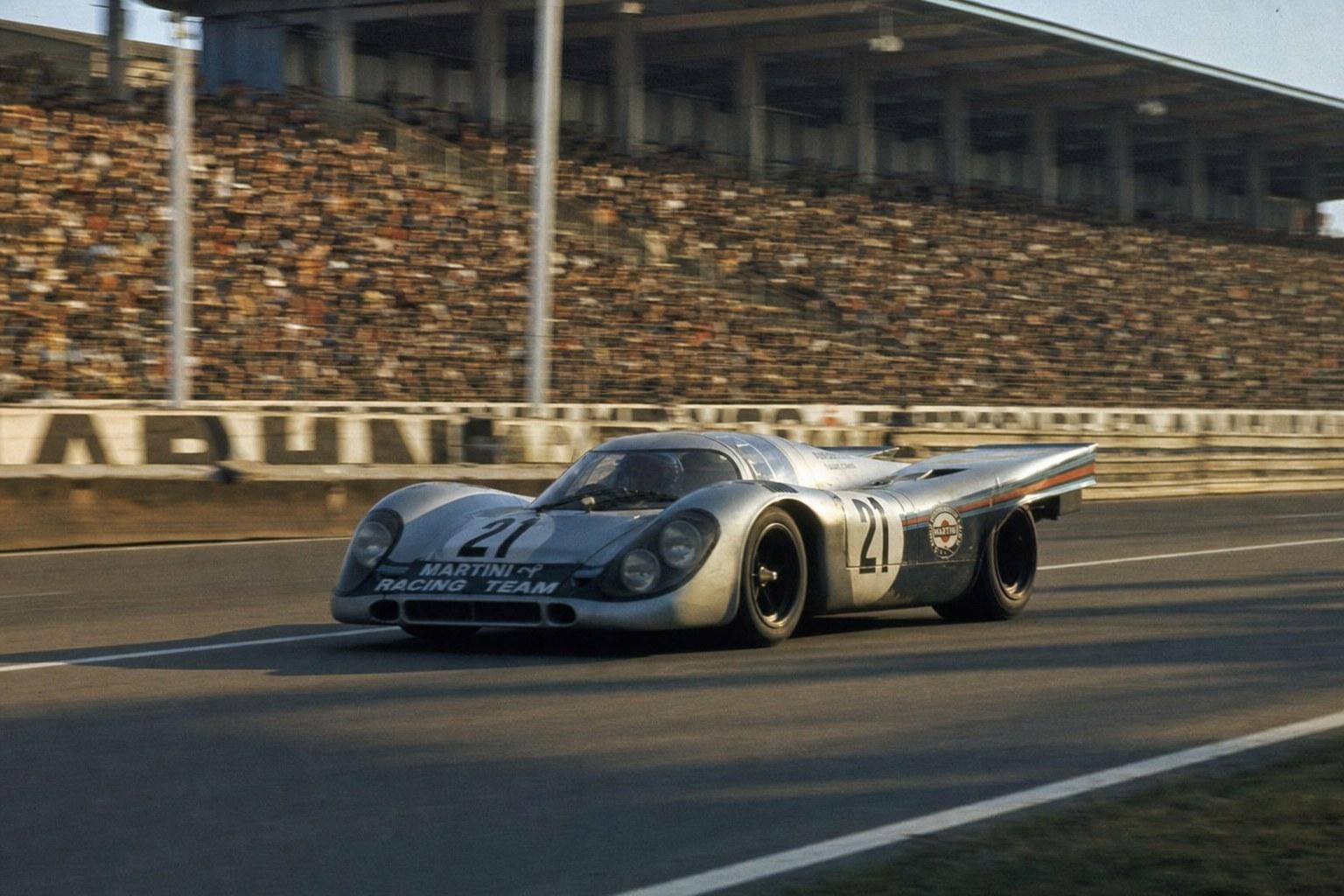 Porsche 917K Martini Racing at speed at Le Mans, packed grandstands behind